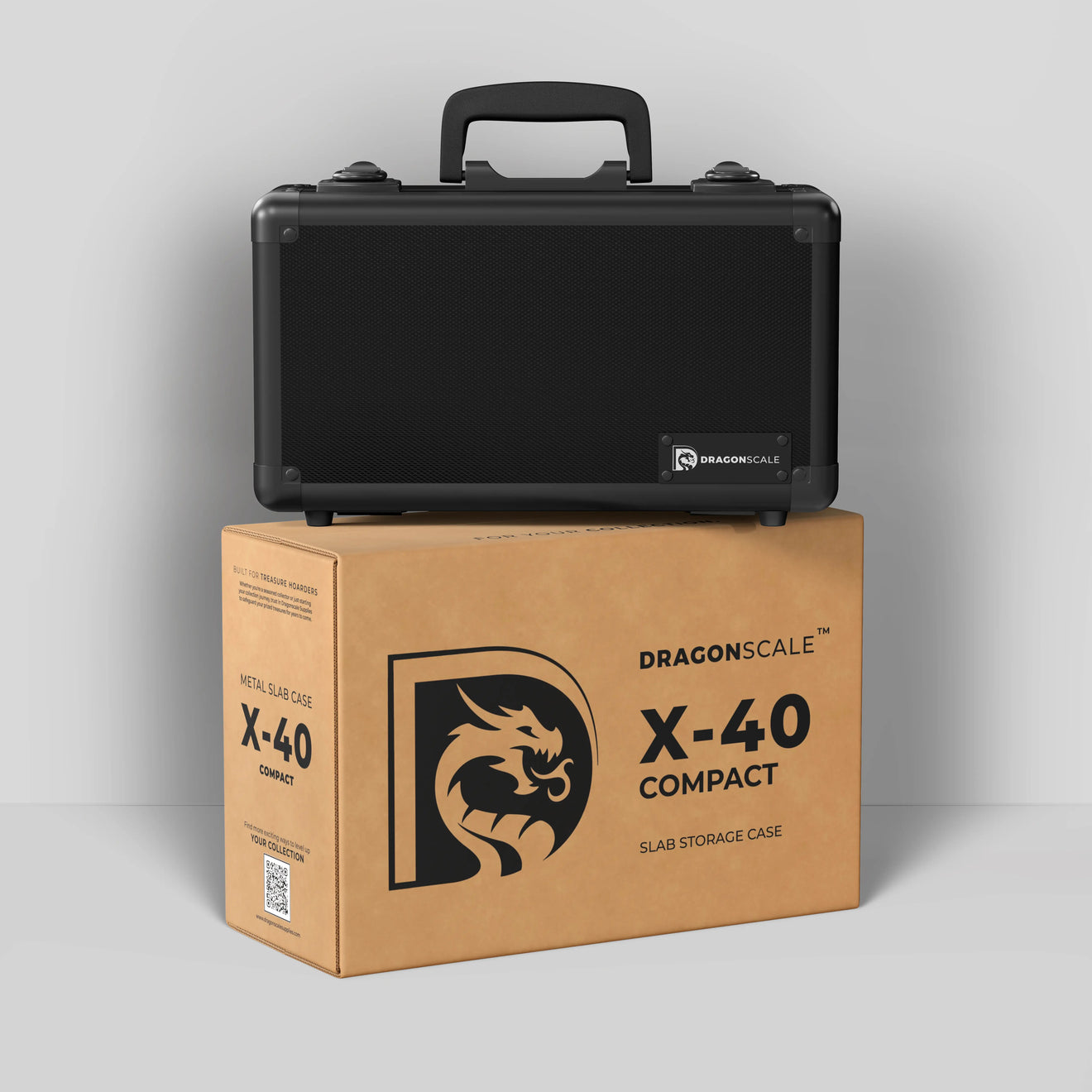 Display and demo view of the Dragonscale Basilisk X-40 Compact metal slab case in carbon black, placed on top of its branded cardboard packaging box.