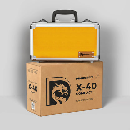 Display and demo view of the Dragonscale Basilisk X-40 Compact metal slab case in gold, placed on top of its branded cardboard packaging box.